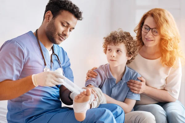 Spaventato ragazzo premendo labbra mentre guardando il medico — Foto Stock