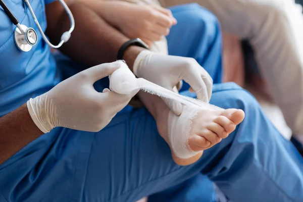 Close-up de pé ferido que estar sobre os médicos joelhos — Fotografia de Stock