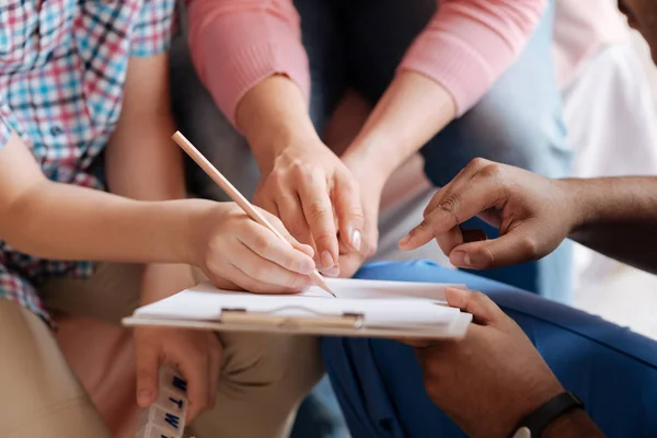 Close up of different hands that pointing at paper — Stock Photo, Image