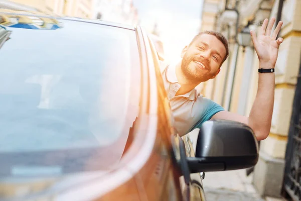 Homem encantador acenando olá de seu carro para um transeunte — Fotografia de Stock