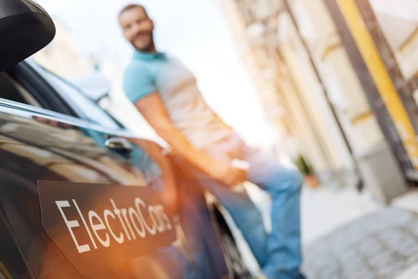 Młody mężczyzna stojący w pobliżu jego nowy samochód elektryczny — Zdjęcie stockowe