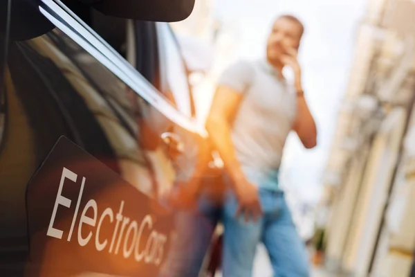 Jovem falando ao telefone perto de seu e-car — Fotografia de Stock