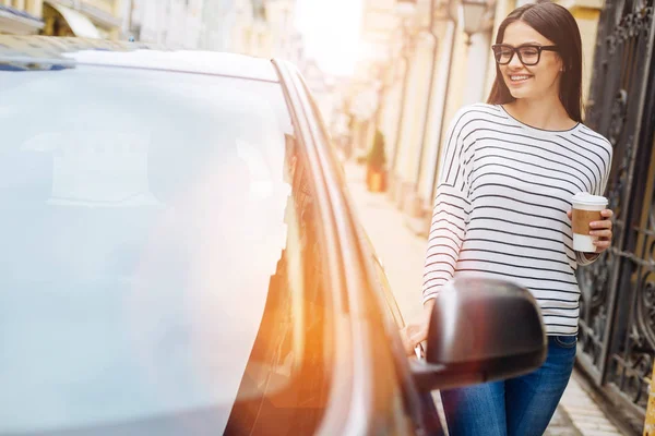 Mulher bonita com xícara de café tocando seu carro — Fotografia de Stock