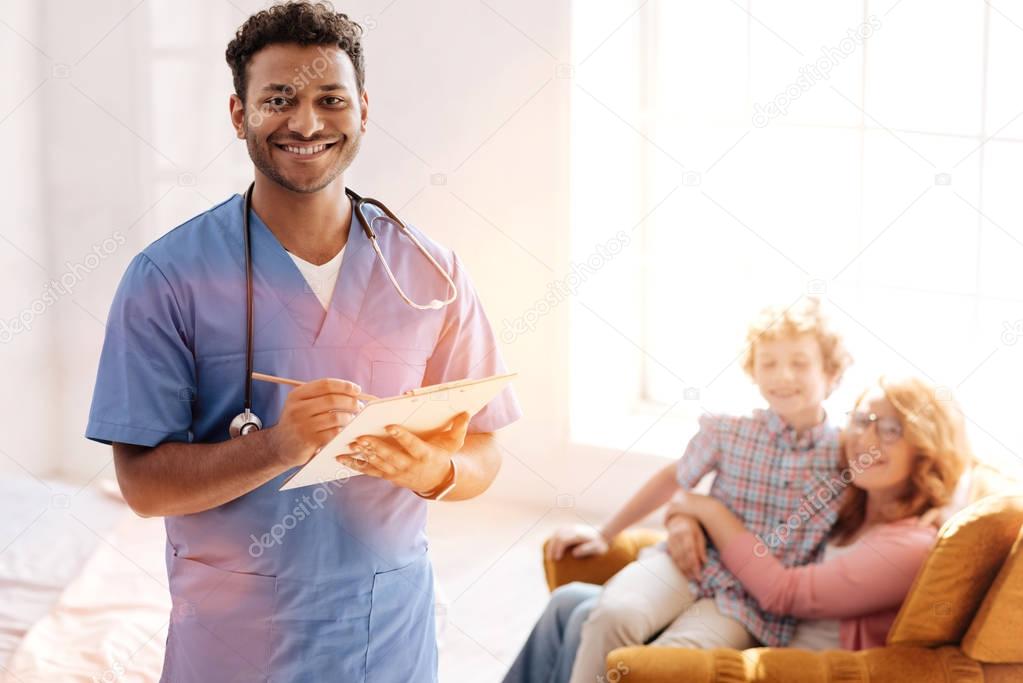 Positive delighted dark-skinned doctor that posing on camera