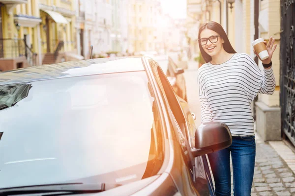 Kobieta radosny stojący w pobliżu samochodu i macha na kamery — Zdjęcie stockowe