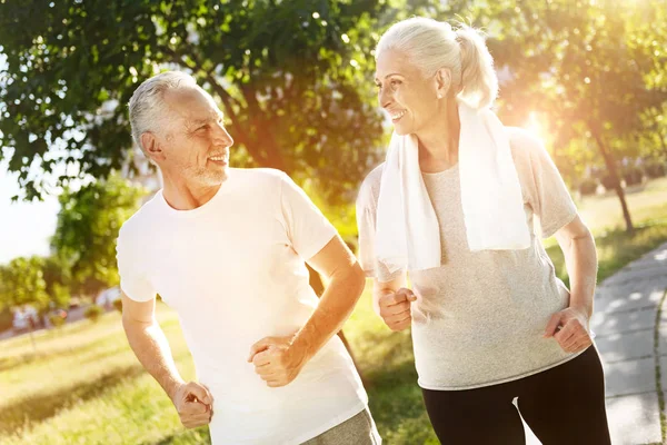 Cheerful retired smiling couple jogging together