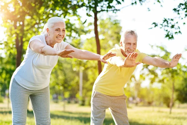 Радостная старшая пара делает спортивные упражнения вместе — стоковое фото