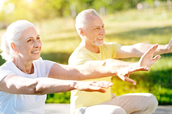 Overjoyed aged couple training in the park