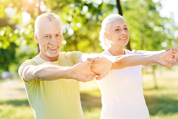 Joyful aged couple enjoying sport exercises