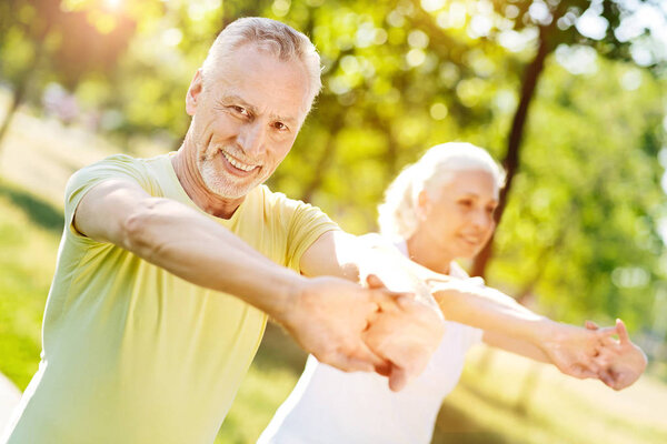 Delighted smiling aged couple enjoying sport exercises