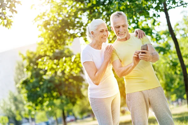 Радостная пара на пенсии с помощью смартфона в парке — стоковое фото