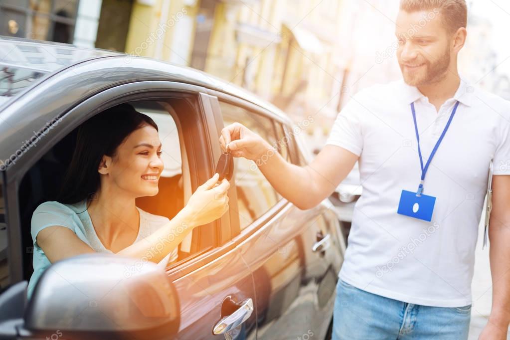Car rental agency employee giving car keys to woman