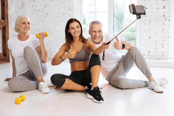 Positiv glad Fitnesscoach holding monopod med telefon — Stockfoto