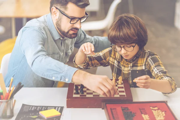 Bonito hombre inteligente enseñando a su hijo a jugar ajedrez — Foto de Stock