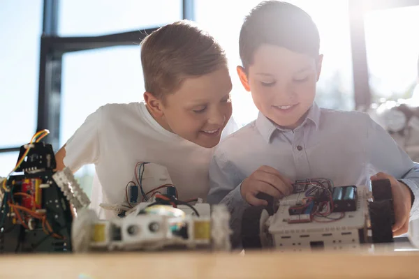 Merry boy observing his friend working on new robot — Stock Photo, Image