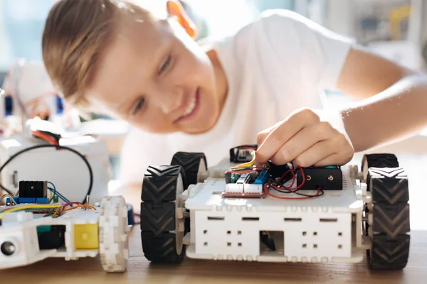 Fair-haired boy adjusting wires in robotic car — Stock Photo, Image