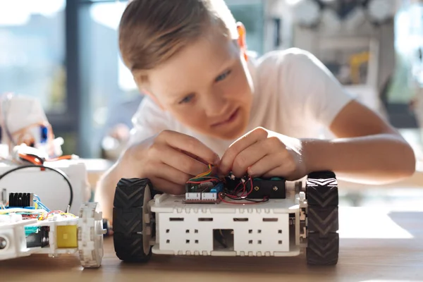 Trevlig pojke ansluta kablarna i robotic fordon — Stockfoto