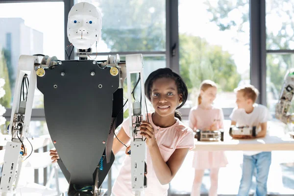 Bir robot arkasından kameraya gülümseyen güzel kız