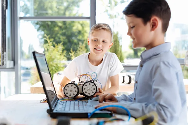 Angenehmer Junge, der auf den Bildschirm seines Laptops schaut — Stockfoto