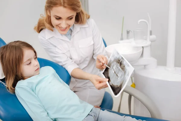 Angenehme junge Zahnärztin zeigt dem Mädchen ihr Röntgenbild — Stockfoto