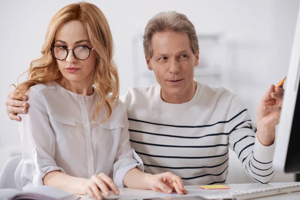 Flirten volwassen office manager knuffelen jonge vrouw aan het werk — Stockfoto