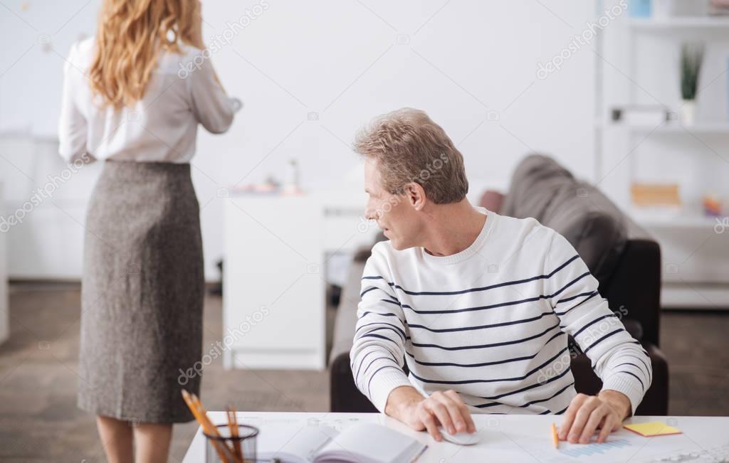 Flirting mature worker looking at young woman body at work
