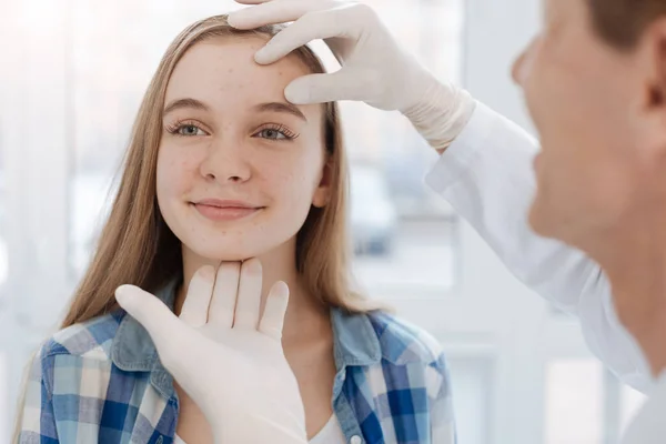 Dermatologista cuidadoso examinando o rosto do paciente no trabalho — Fotografia de Stock