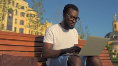 Proje açık havada için bilgisayar kullanan olumlu Afrikalı-Amerikalı adam