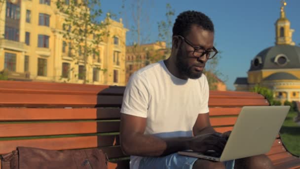 Sério homem milenar trabalhando no laptop fora — Vídeo de Stock