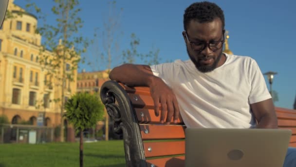 Fokuseret mand viser lyst smil, mens du arbejder på laptop – Stock-video