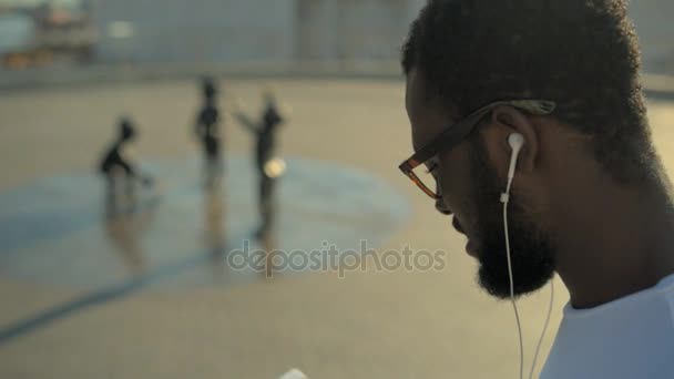 Zijaanzicht op Afro-Amerikaanse man, luisteren naar muziek in openlucht — Stockvideo