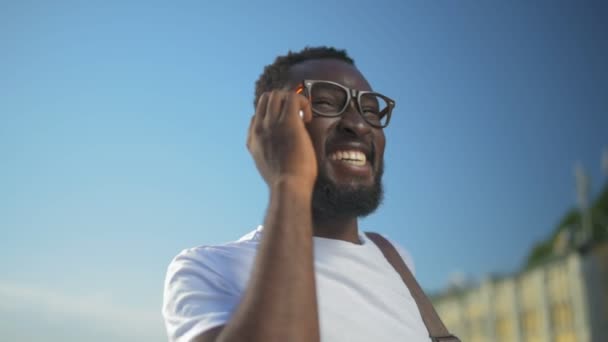 Парень смеется во время телефонного разговора — стоковое видео