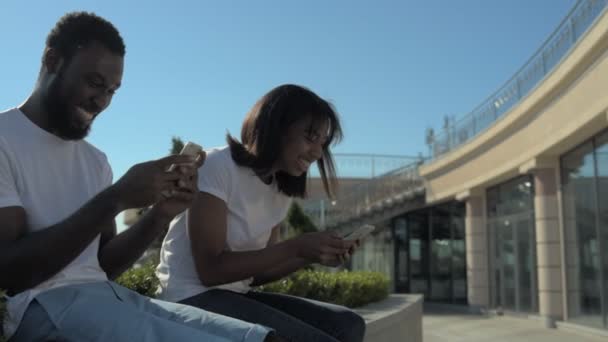 Adorável casal afro-americano mensagens uns aos outros em telefones — Vídeo de Stock