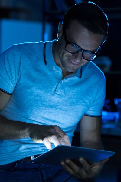 Hombre inteligente optimista leyendo algo en su tableta —  Fotos de Stock