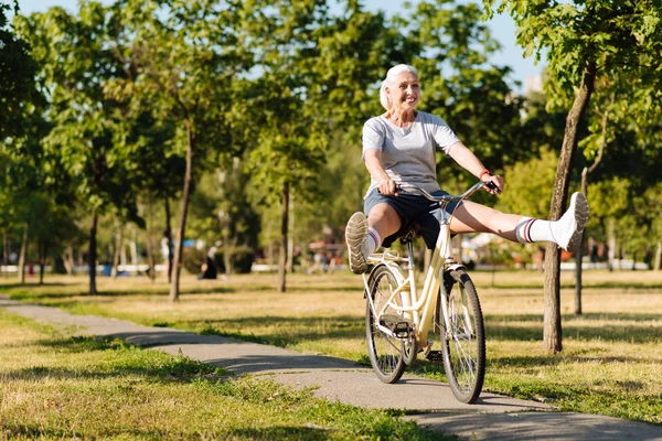 Mujer mayor alegre montando una bicicleta — Foto de Stock