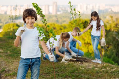 Kendine güvenen çocuk bir ağaca yakın kamera poz