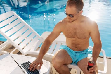 Yanık tenli adam browsing belgili tanımlık enterne havuzu yakınlarında