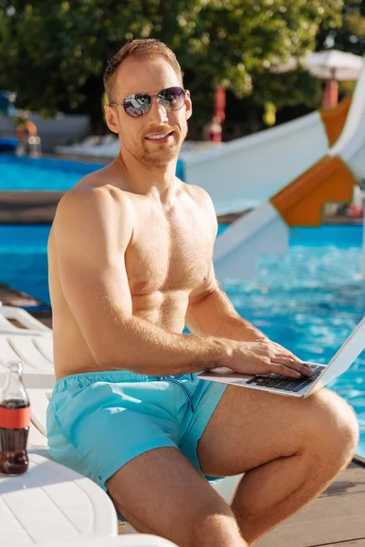 Yüzme Havuzu yanında dizüstü bilgisayar ile oturan atletik adam