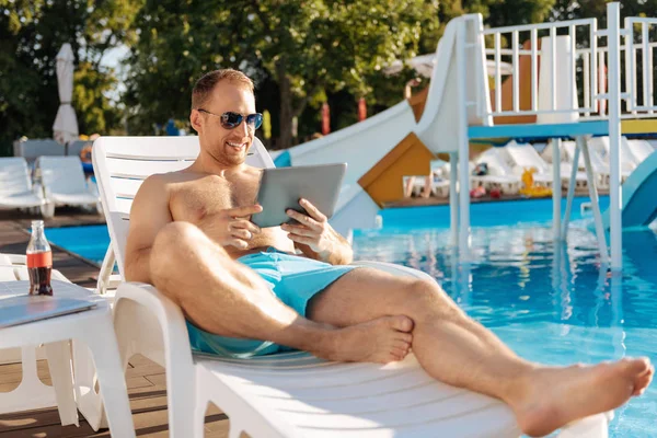 Agradable hombre viendo una película en la tableta cerca de la piscina — Foto de Stock