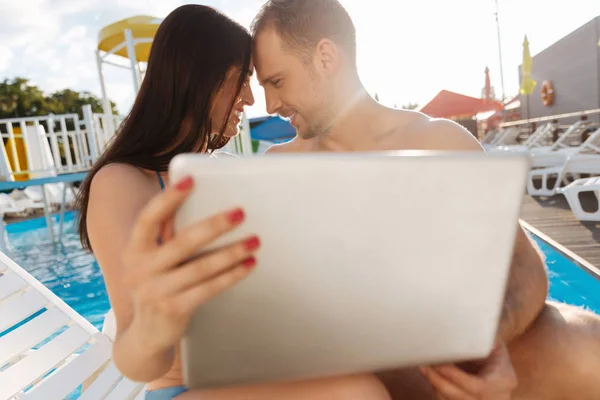 Happy couple sitting forehead to forehead near pool — Stock Photo, Image