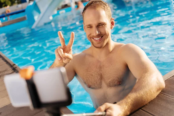 Hombre sonriente mostrando un signo V mientras toma selfie — Foto de Stock