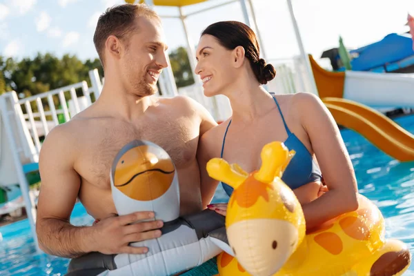 Happy couple in swim rings looking at each other lovingly — Stock Photo, Image