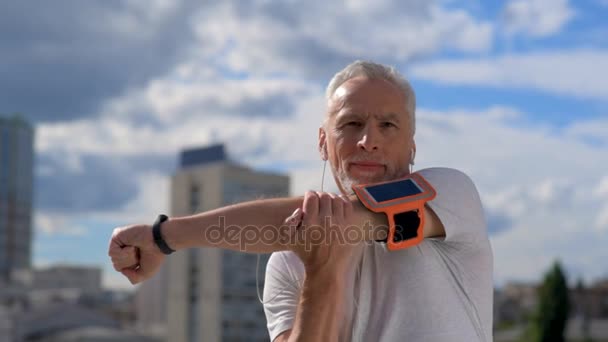 Hombre mayor seguro estratando sus brazos al aire libre — Vídeo de stock