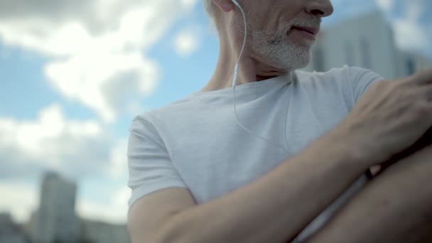 Homem idoso positivo usando sua braçadeira para escolher a música certa — Vídeo de Stock