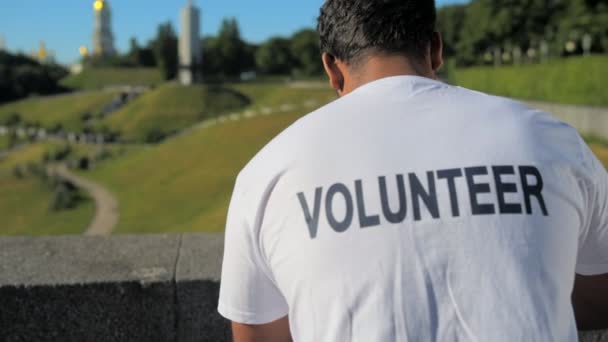 Dolly disparo de un tipo voluntario masculino sentado al aire libre — Vídeos de Stock