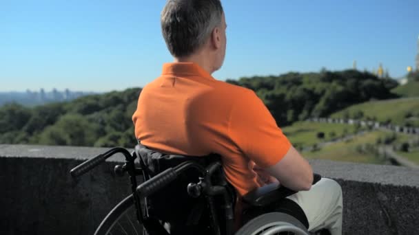 Geconcentreerd wheelchaired man geniet van het uitzicht over de kerk — Stockvideo