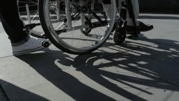 Zeitlupe einer freundlichen Person, die einen Rollstuhlfahrer schubst — Stockvideo
