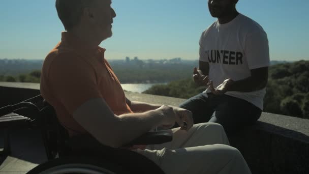 Bénévole positif parlant avec un homme en fauteuil roulant — Video