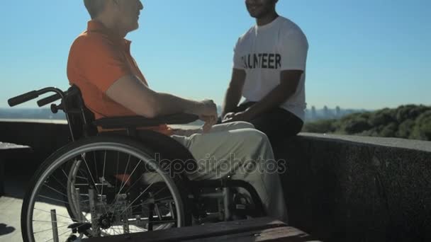 Joyful volunteer talking with a wheelchaired man — Stock Video