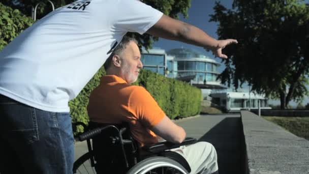 Hasznos hindu önkéntes állandó egy wheelchaired ember a parkban — Stock videók